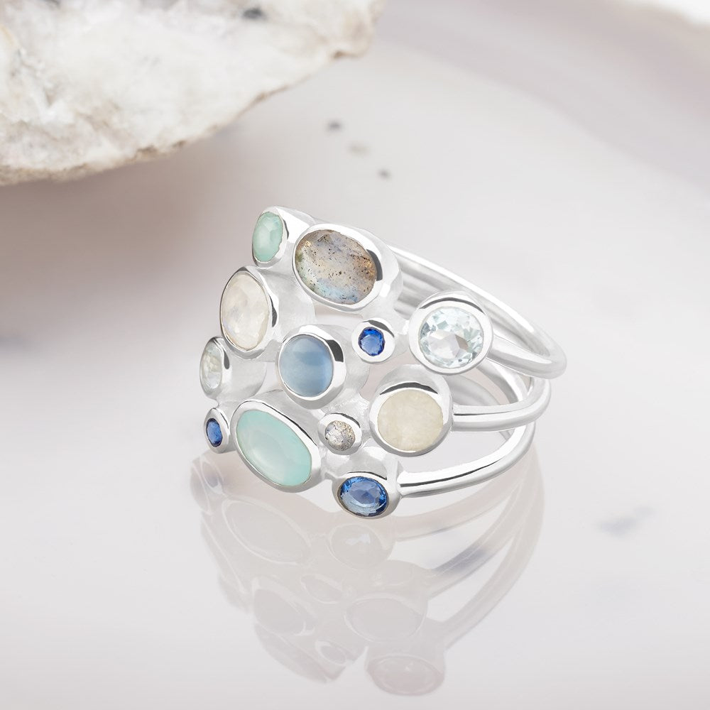 A sterling silver ring with an array of semi-precious stones set within a circular design, featuring labradorite, blue topaz, chalcedony, iolite, and moonstone.
