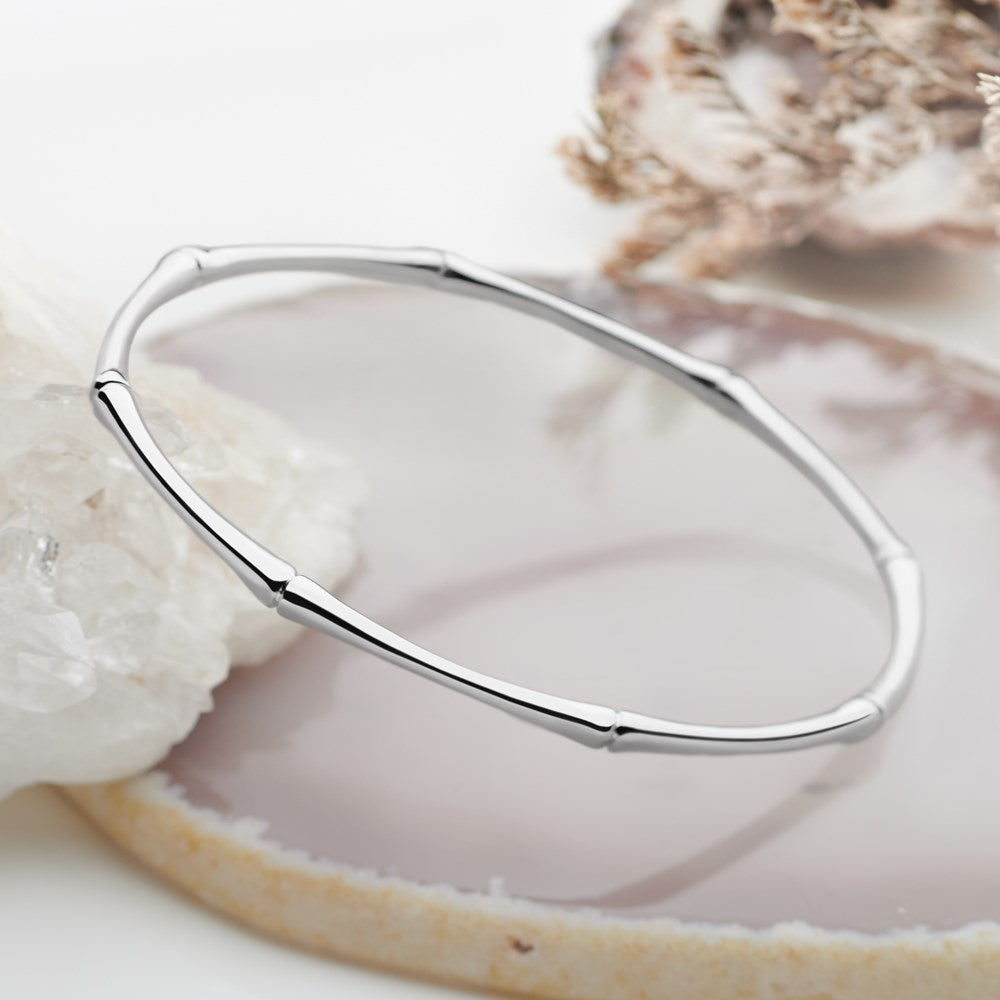 A high polish finish silver bangle with a bamboo design, displayed on a white surface.