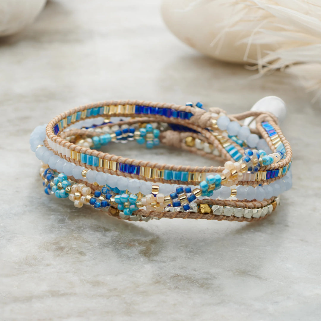 Stack of beaded bracelets with blue and gold accents on a light background