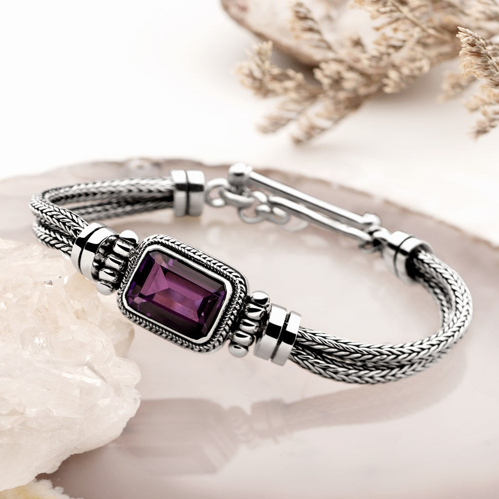 Silver bracelet with a purple gemstone on a white background