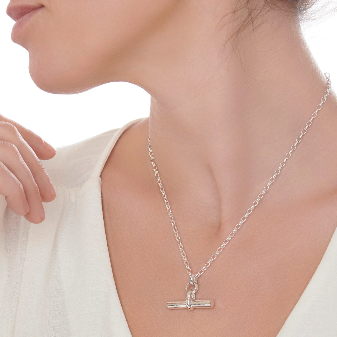 Silver necklace with a unique pendant worn by a person against a neutral background