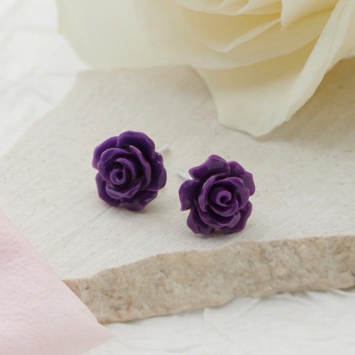 Purple rose earrings on a soft fabric background
