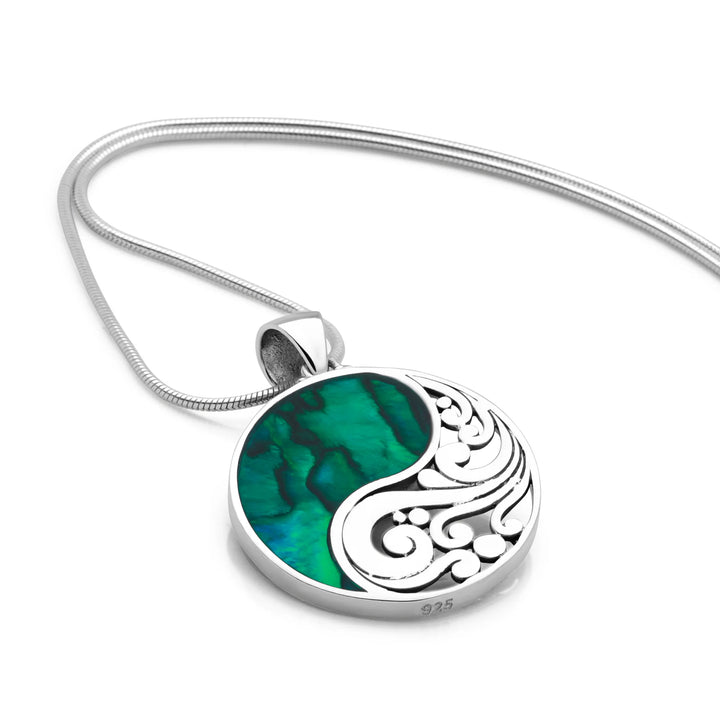 Silver pendant with green inlay on a white background