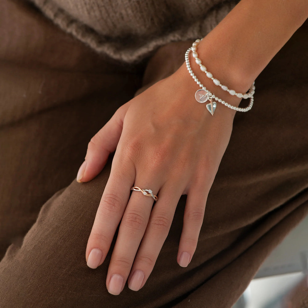 An eternity ring with two zirconia stones, entwined with silver and rose gold bands.