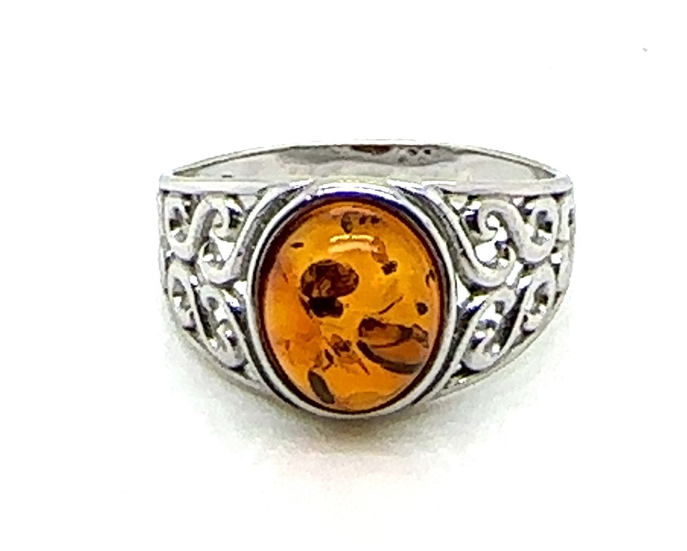 Silver ring with a amber stone on a white background celtic desing.
