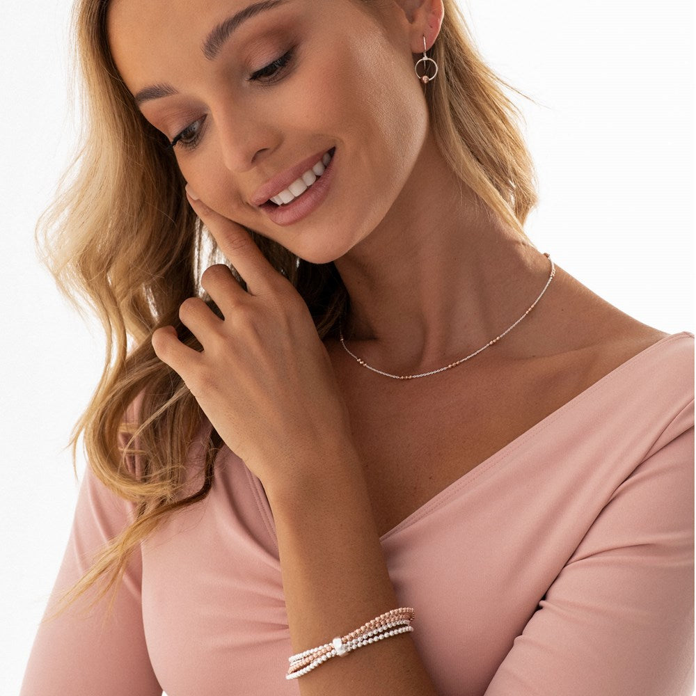 A pair of silver hoop earrings with rose gold plated moons attached to them, displayed against a model.