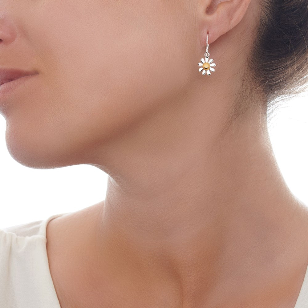 A pair of silver drop earrings with gold plate accents in the shape of daisies on model.