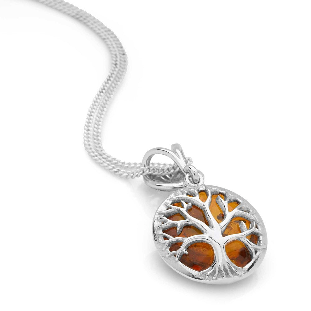 A silver pendant with a tree of life design and a cabochon of amber swinging below it, attached to a silver chain.