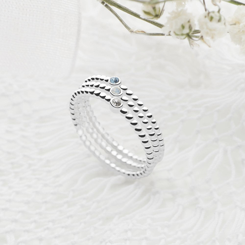 Three silver rings with beaded bands and a central faceted crystal design in a stack formation.