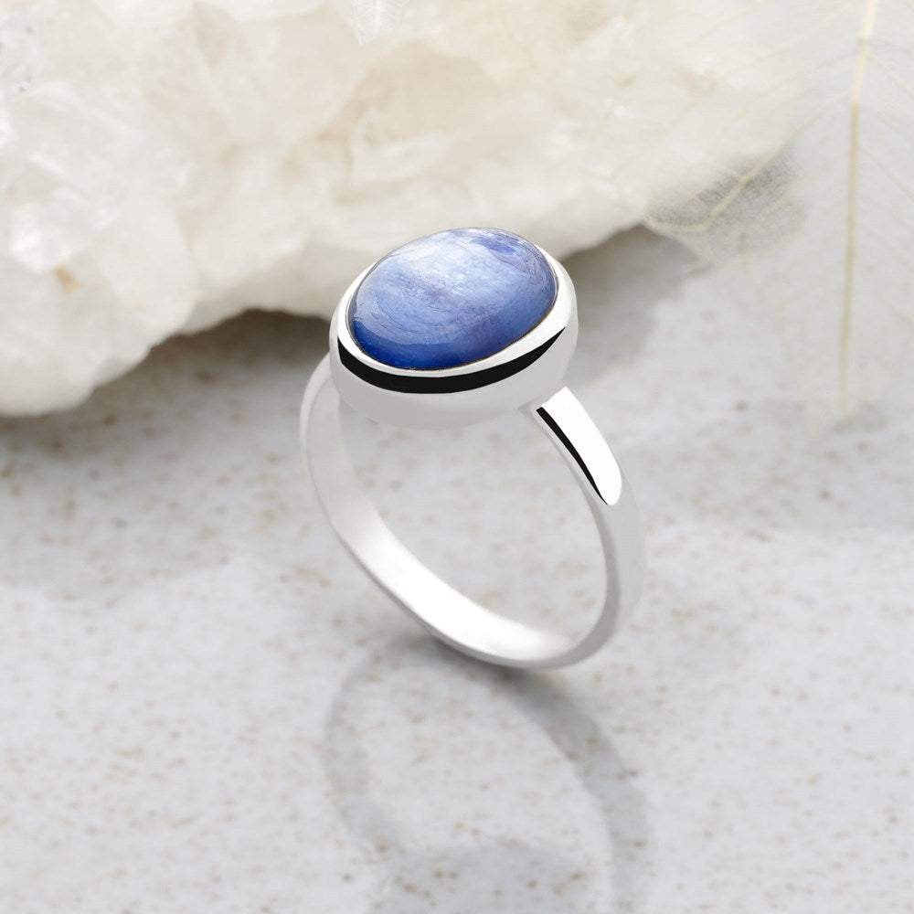A ring with a central blue kyanite cabochon, set in a high polish finish 925 sterling silver band.