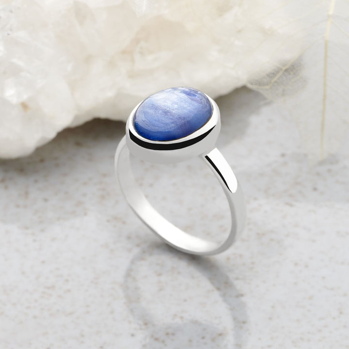 A ring with a central blue kyanite cabochon, set in a high polish finish 925 sterling silver band.